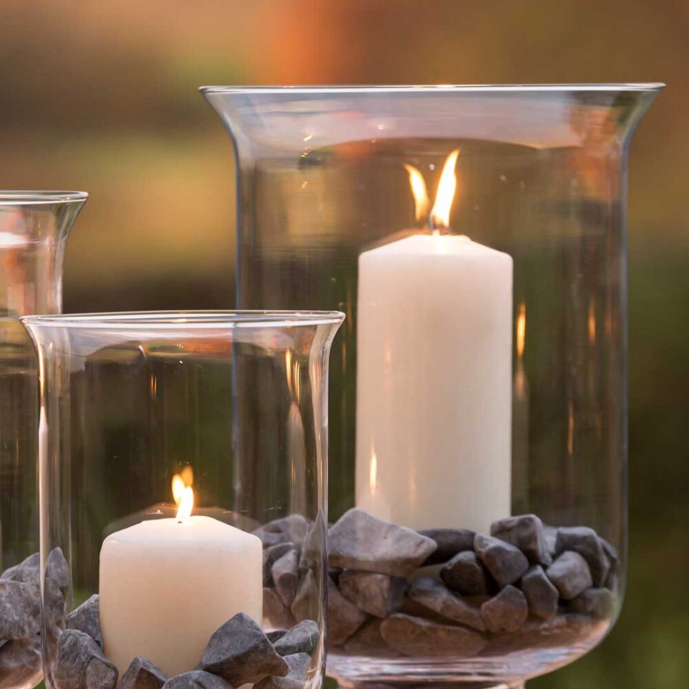 Festival Glass Hurricane Lamps - large and small versions pictured on an outdoor table.