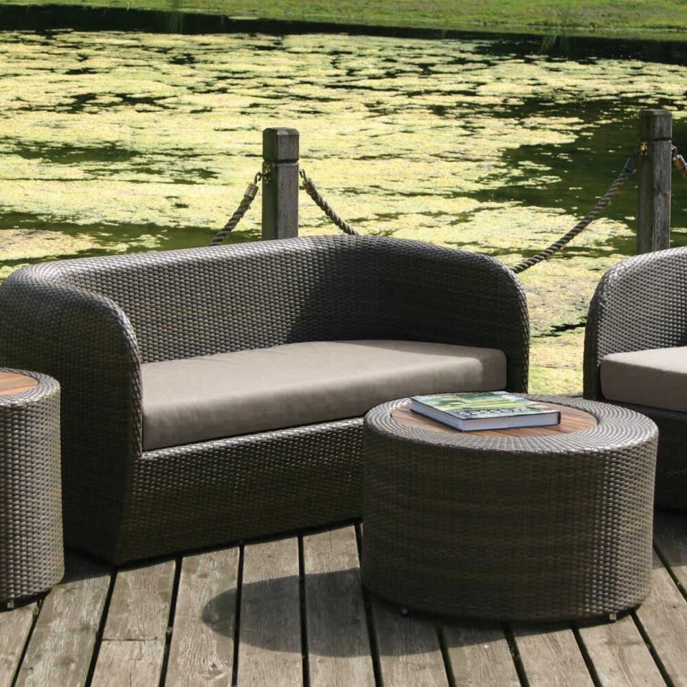 A garden setting with the concentirc table and tubby sofa and armchair in summergrass