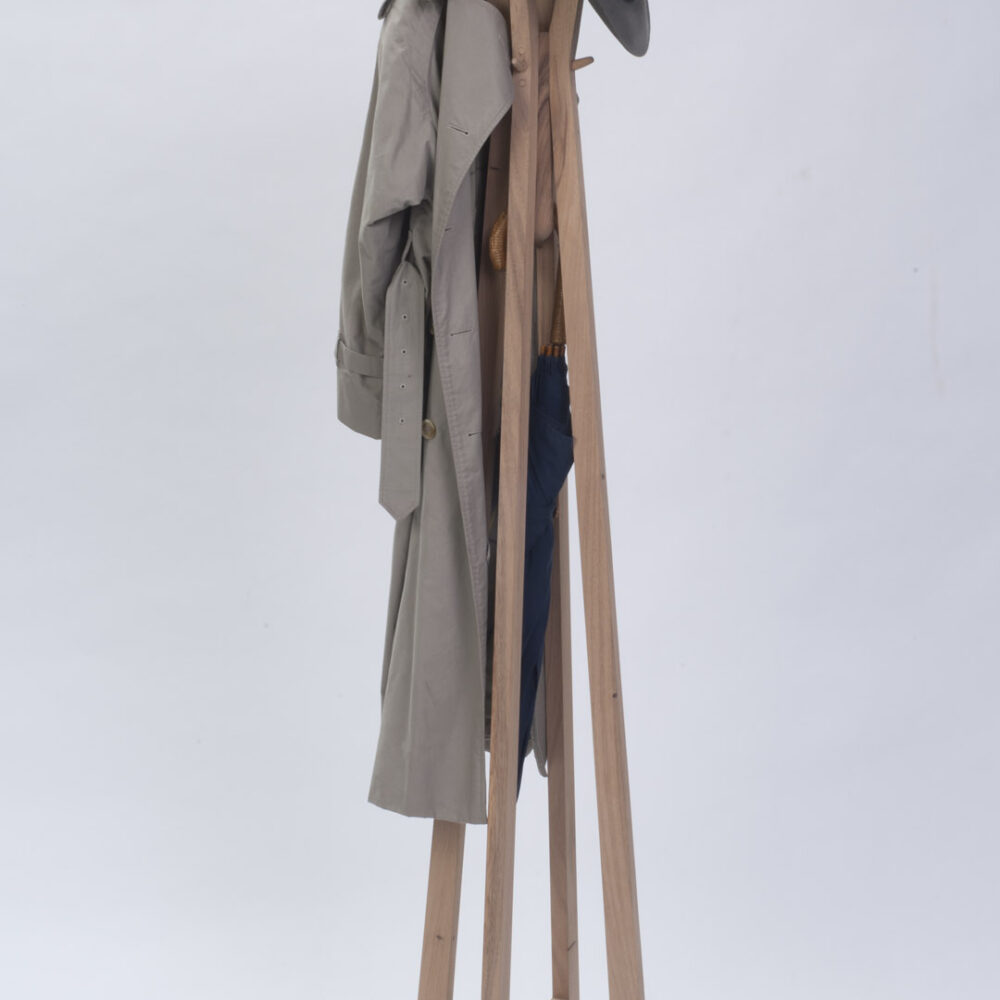 Totem wooden coat and hat stand shown with a raincoat, hat and umbrella.