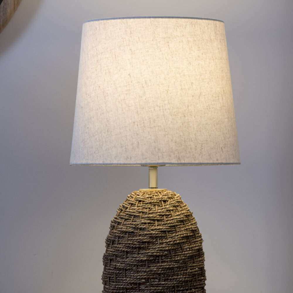 Mali woven table lamp - woven table lamp with natural shade softly lit on a sideboard with a mirror behind.