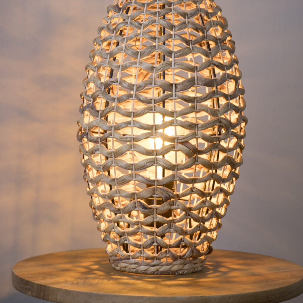 Rabat woven table lamp - shade-less lamp lit on a sideboard - casts a soft, warm light.