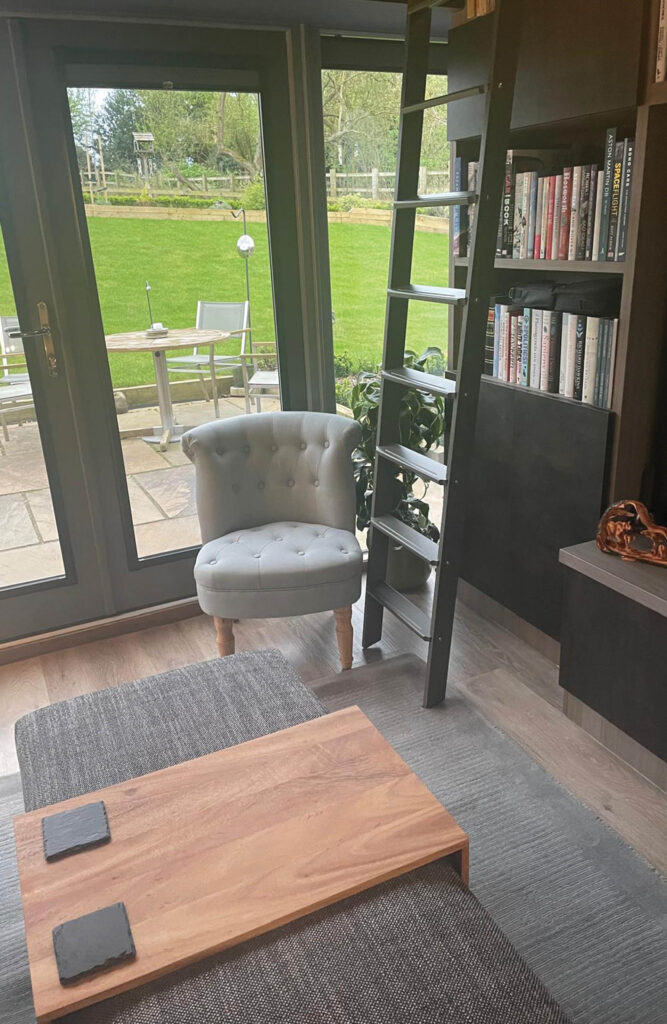 Marylebone upholstered coffee table in Newport greys fabric, pictured in customer living space / home library - complete with ladder.